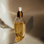 Close-up of a perfume bottle elegantly placed on a reflective surface with warm lighting.