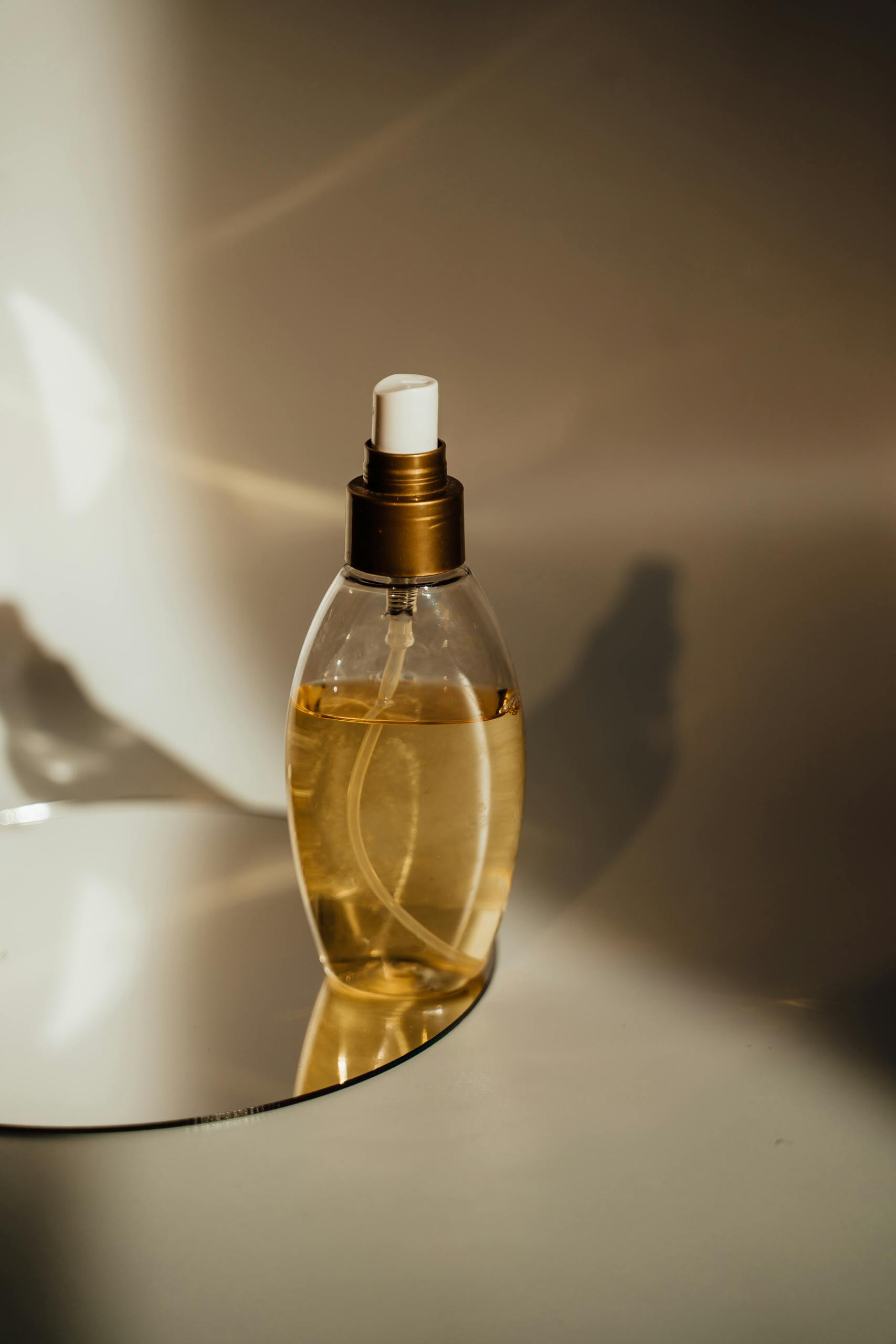 Close-up of a perfume bottle elegantly placed on a reflective surface with warm lighting.
