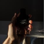 A man's hand holds a Givenchy perfume bottle with dramatic lighting.